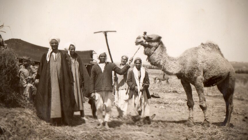 A group of five Egyptian men and children, one man is holding the reins of a camel.