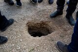 People stand around a small hole in the ground that six Palestinian prisoners escaped through outside Gilboa prison in Israel.