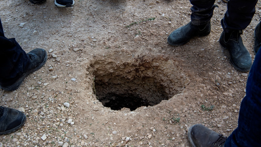 People stand around a small hole in the ground that six Palestinian prisoners escaped through outside Gilboa prison in Israel.