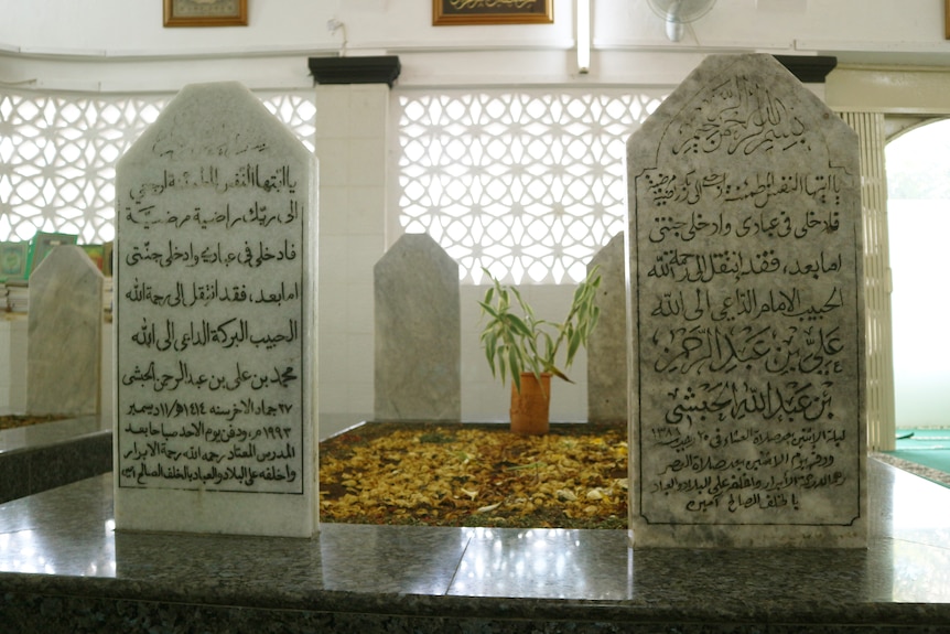 Two tombstones with Arabic writing sit side by side inside a cemetery room.