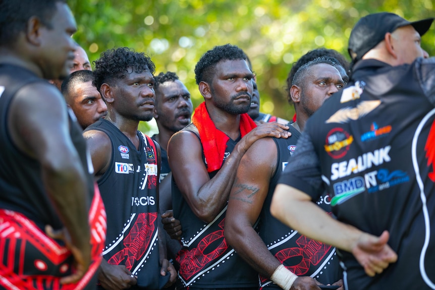 Men playing Australian Rules football get coached by their coach