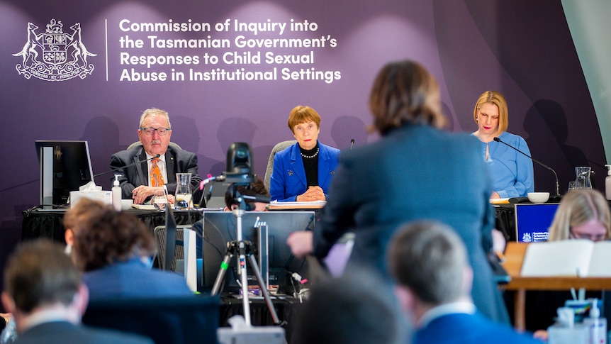 Three commissioners listen to an address at a hearing of the commission of inquiry.