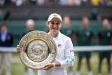 Ash Barty, smiling, holds up her trophy after defeating Karolina Pliskova at Wimbledon.