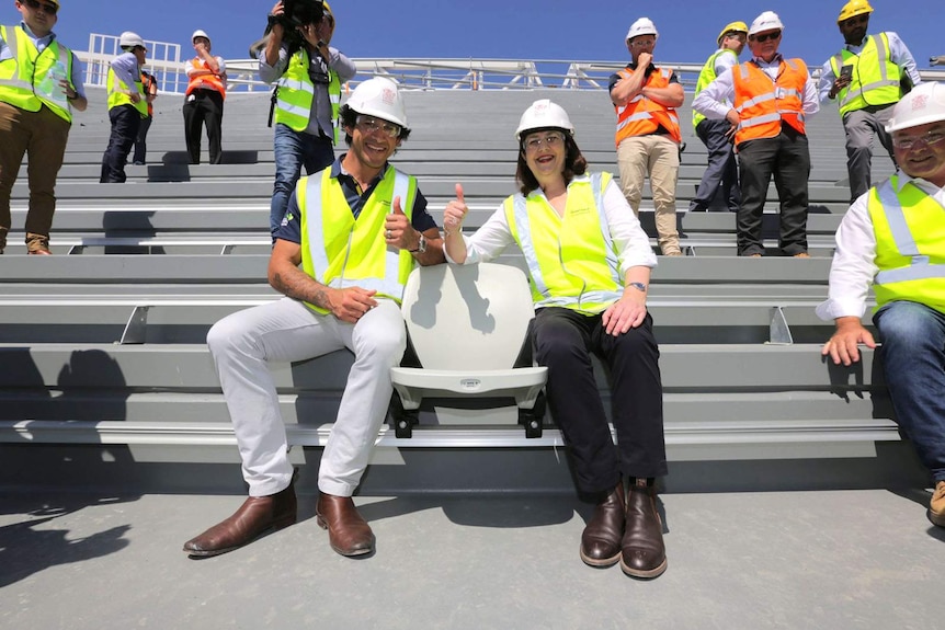 Premier Annastacia Palaszczuk and Johnathan Thurston in hard hats in a stadium under construction