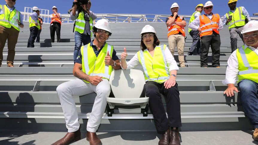 Premier Annastacia Palaszczuk and Johnathan Thurston in hard hats in a stadium under construction