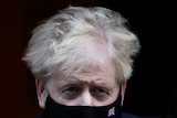 Boris Johnson in a black face mask, with a tiny Union Jack stitched on it 