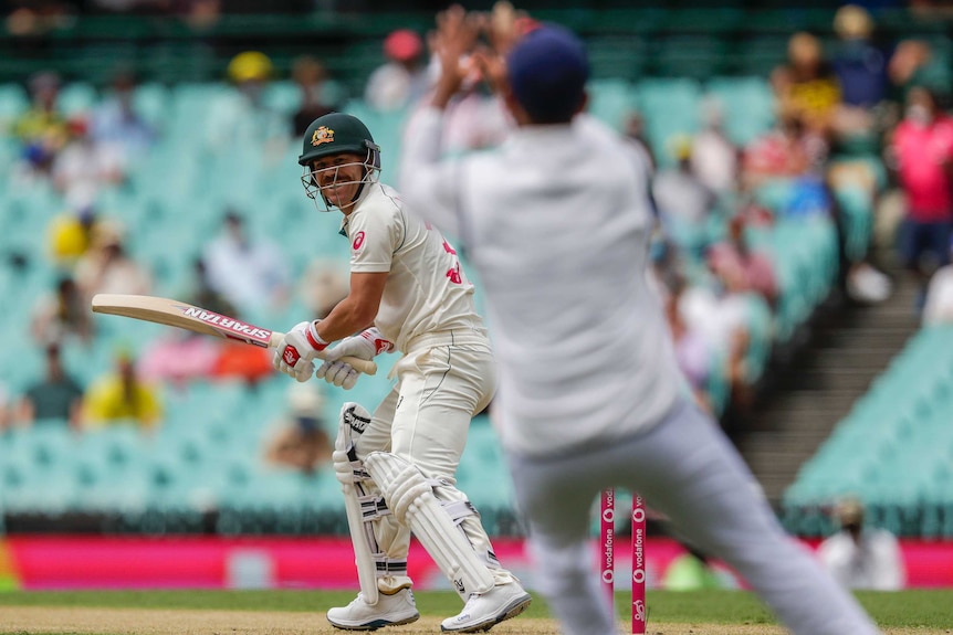 Australia batsman David Warner watches over his shoulder as he is caught out by India's Cheteshwar Pujara at the SCG.