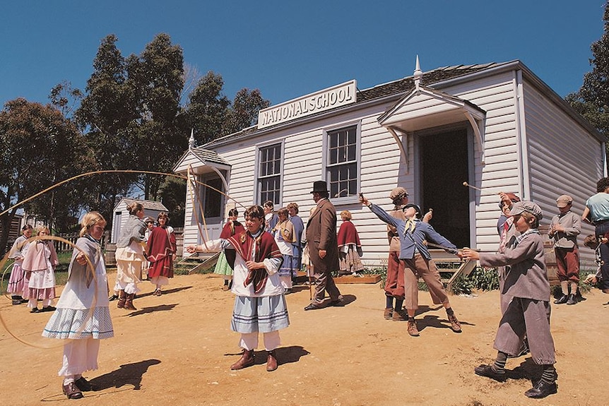 A group of children dressed in colonial clothing playing outside Sovereign Hill's National School building