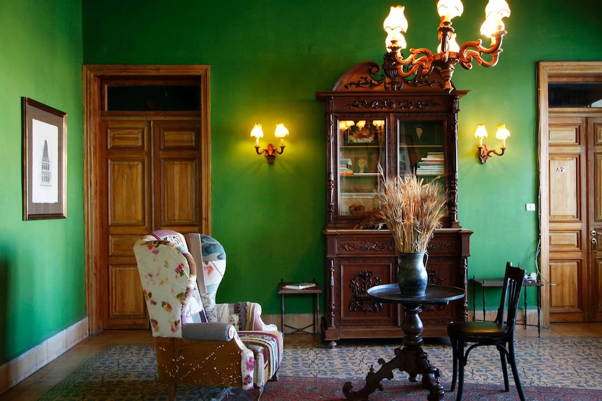 An empty room with green walls in the Palmyra Hotel.