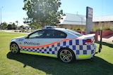 A police car parked on the grass outside a police station.