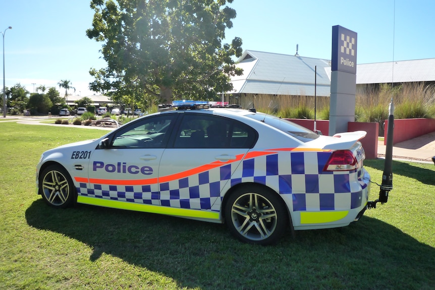 A police car parked on grass outside a police station.