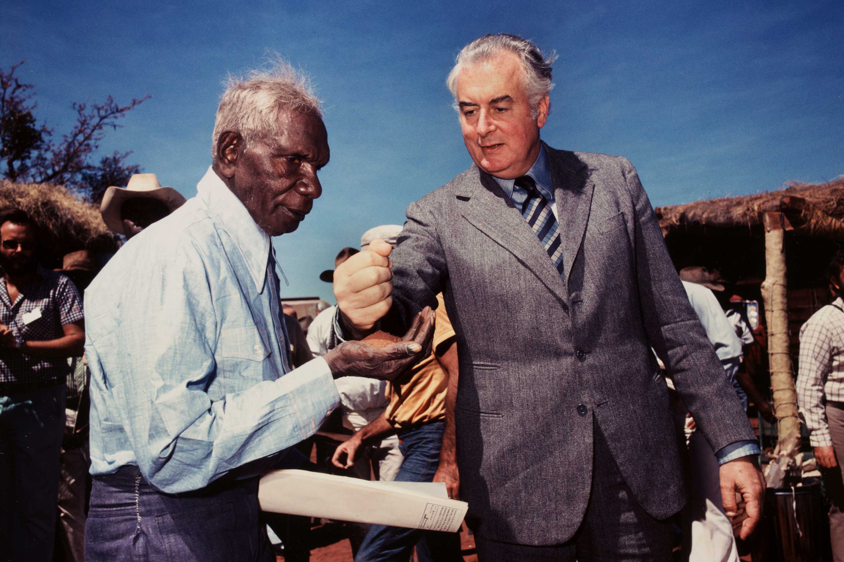 Gough Whitlam puts sand into Vincent Lingiari's hand.