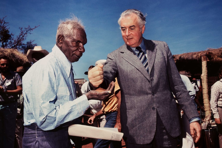 Gough Whitlam pours sand into Vincent Lingiari's hand.