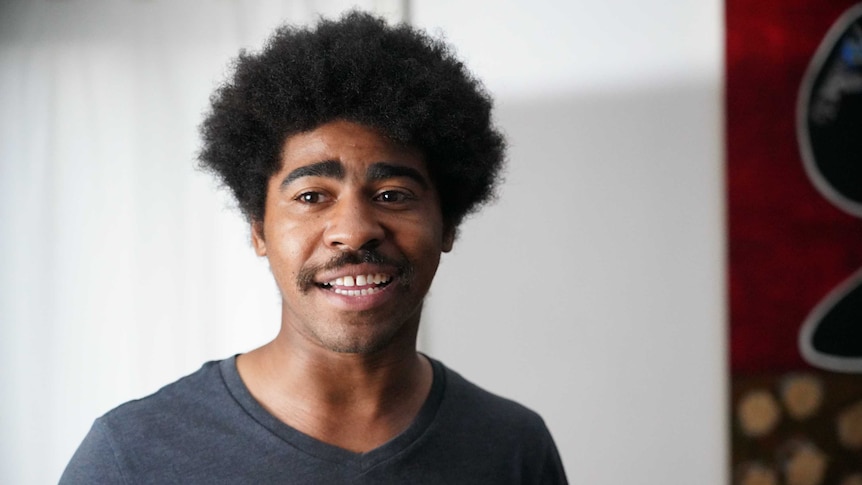 Devin Allen, a young black photographer who has covered the anti-racism movement, smiles slightly and looks off camera.