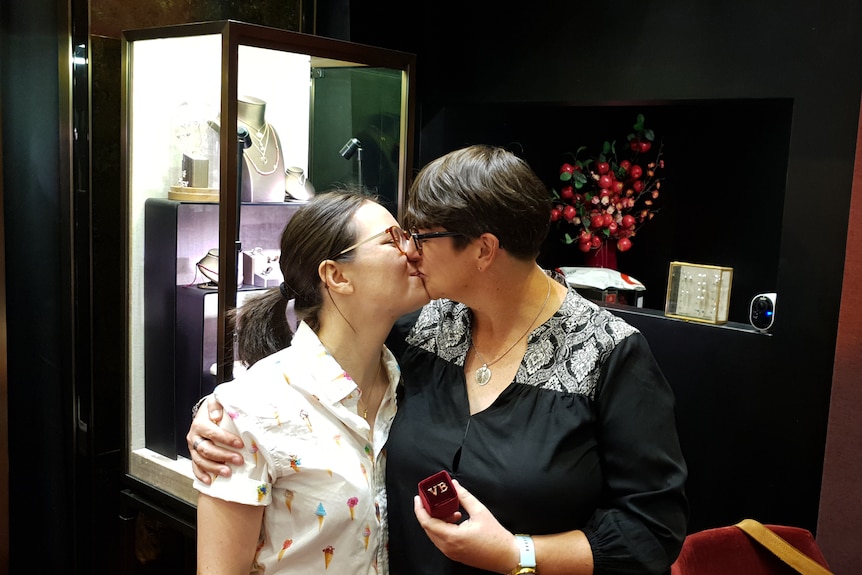 Two women kissing in a jewellery shop. 