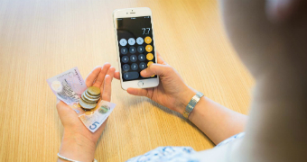 Woman holding a mobile phone and looking at money in her hand.