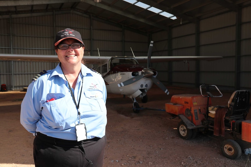 A woman standing in front of an aeroplane in a hanger.