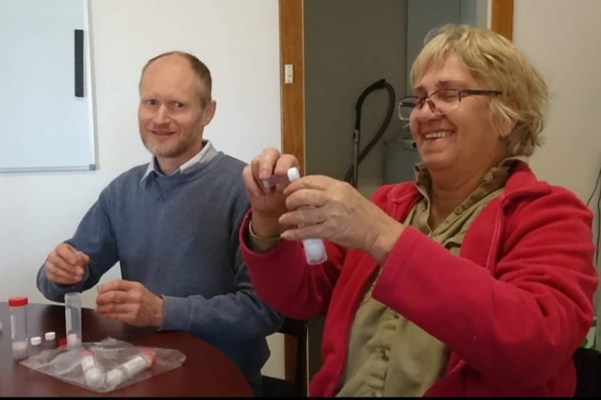 A man and a woman holding test tubes.