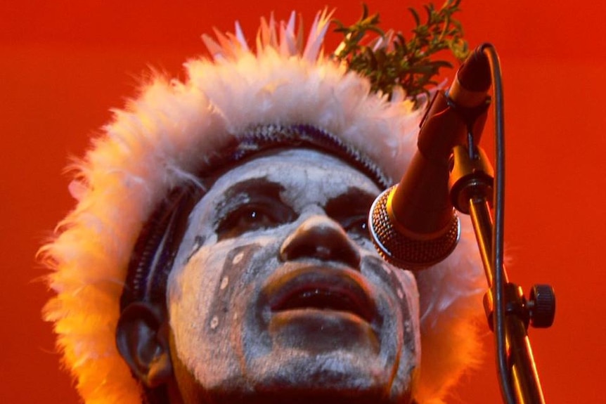 Tight shot of a man singing into a microphone.