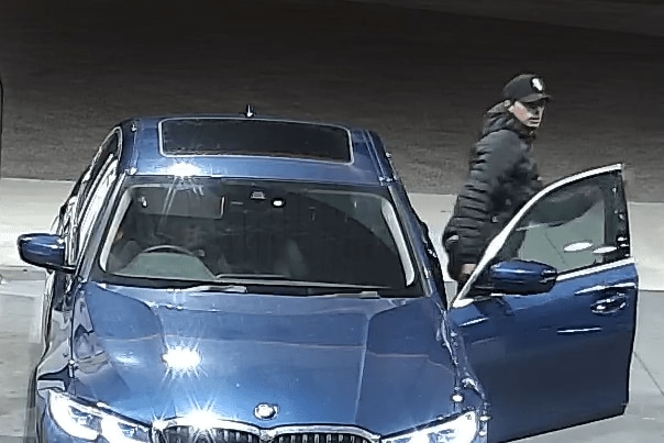 A man stepping out of a blue car.