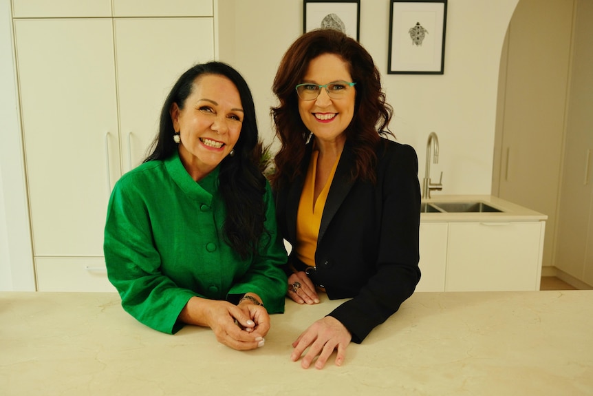 Linda Burney standing next to Annabel Crabb, both lean on a kitchen bench smiling