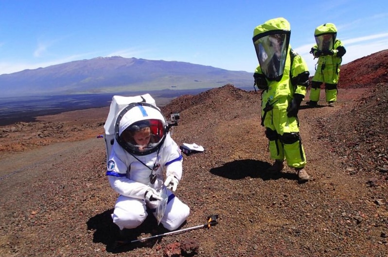 People suited up in space suits on a Mars-like site in Hawaii.
