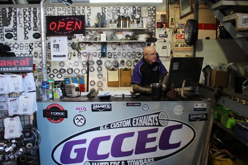 Mechanic on computer with car parts displayed on wall