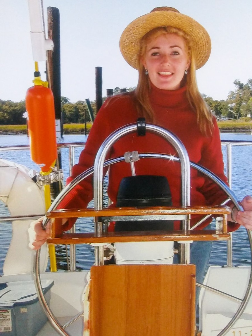 A young blonde woman steering a boat