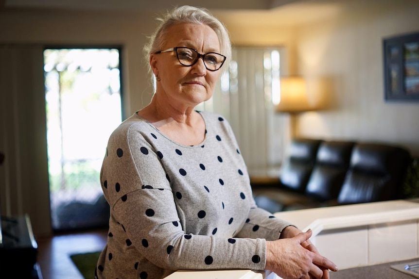 A woman leaning against a kitchen bench