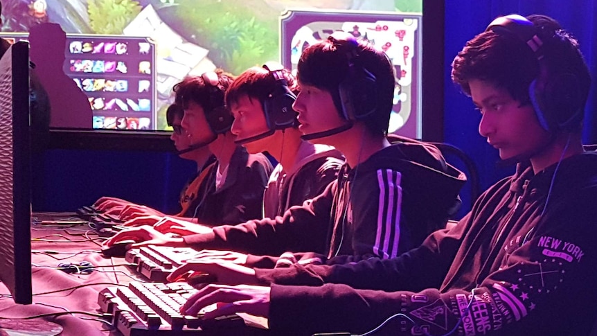 Students sitting in front of a computer playing League of Legends.
