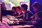 Students sitting in front of a computer playing League of Legends.