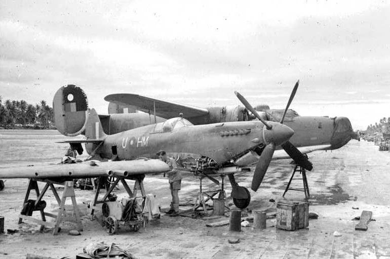 A black and white photo of a Spitfire plane being assembled.