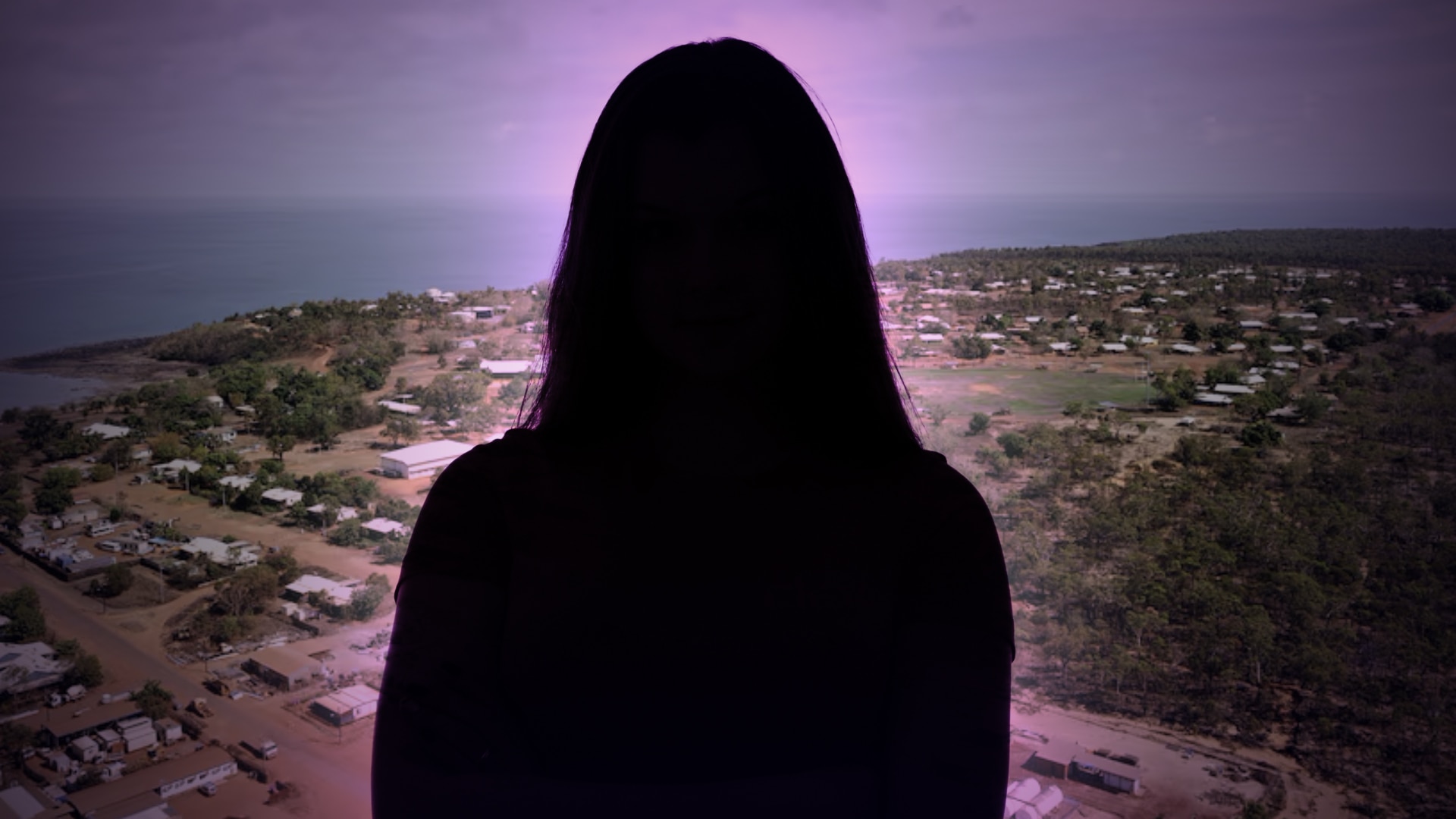 The shadowy outline of a young girl is seen in front of an aerial photo of a rural town
