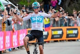 Smiling cyclist Chris Froome pumps the air as he crosses the line