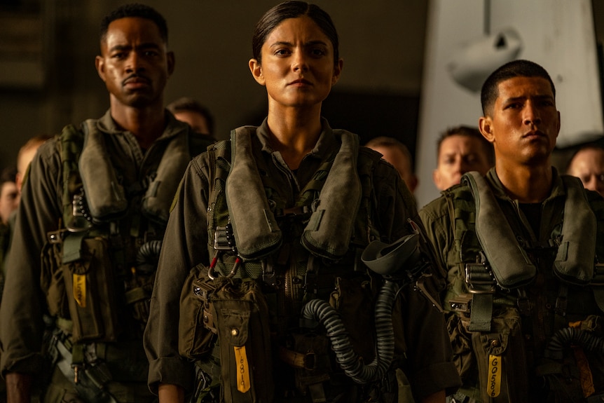 Black man and Latinx woman and man stand to attention wearing khaki-coloured airforce uniforms.