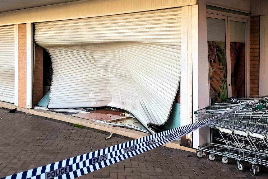 A crumpled roller door after it was smashed by a car.