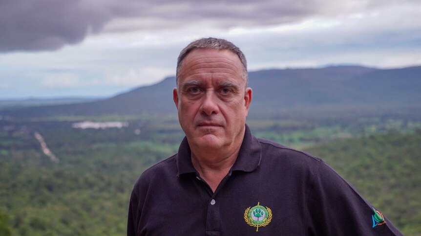 A man stands on a hill overlooking Thai jungle