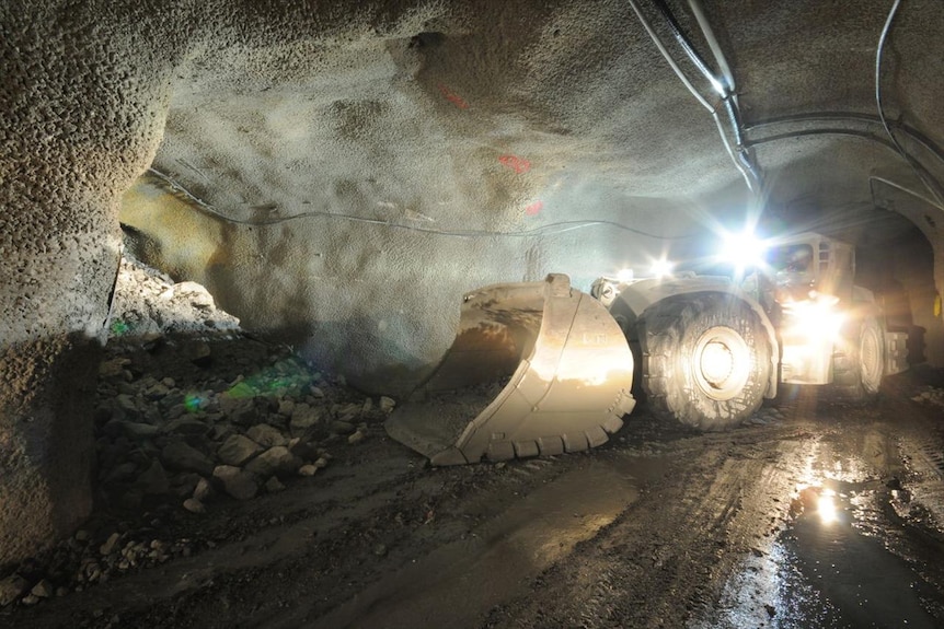 A tractor with a big scoop underground about to shovel rocks.