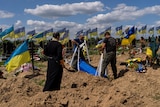 Undertakers lower the coffin of Ukrainian serviceman in dirty patch