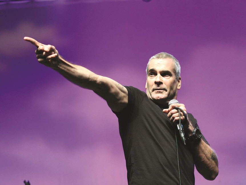 Henry Rollins on stage pointing at a crowd, grimacing