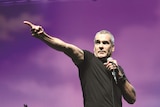 Henry Rollins on stage pointing at a crowd, grimacing