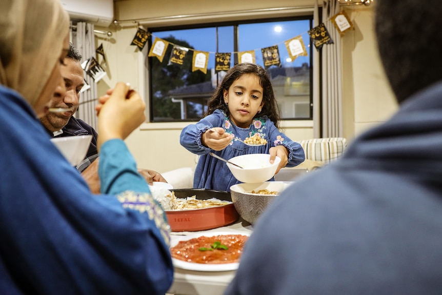 a young girl holding a spoon at a table