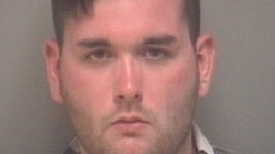 Police mug shot of dark-haired young man in black and white shirt.