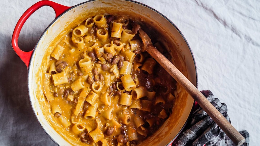 A cast iron pot filled with a thick pasta and bean soup, comfort food for winter.
