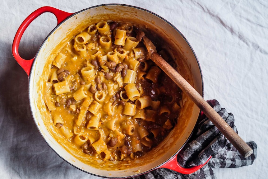 A cast iron pot filled with a thick pasta and bean soup, comfort food for winter.