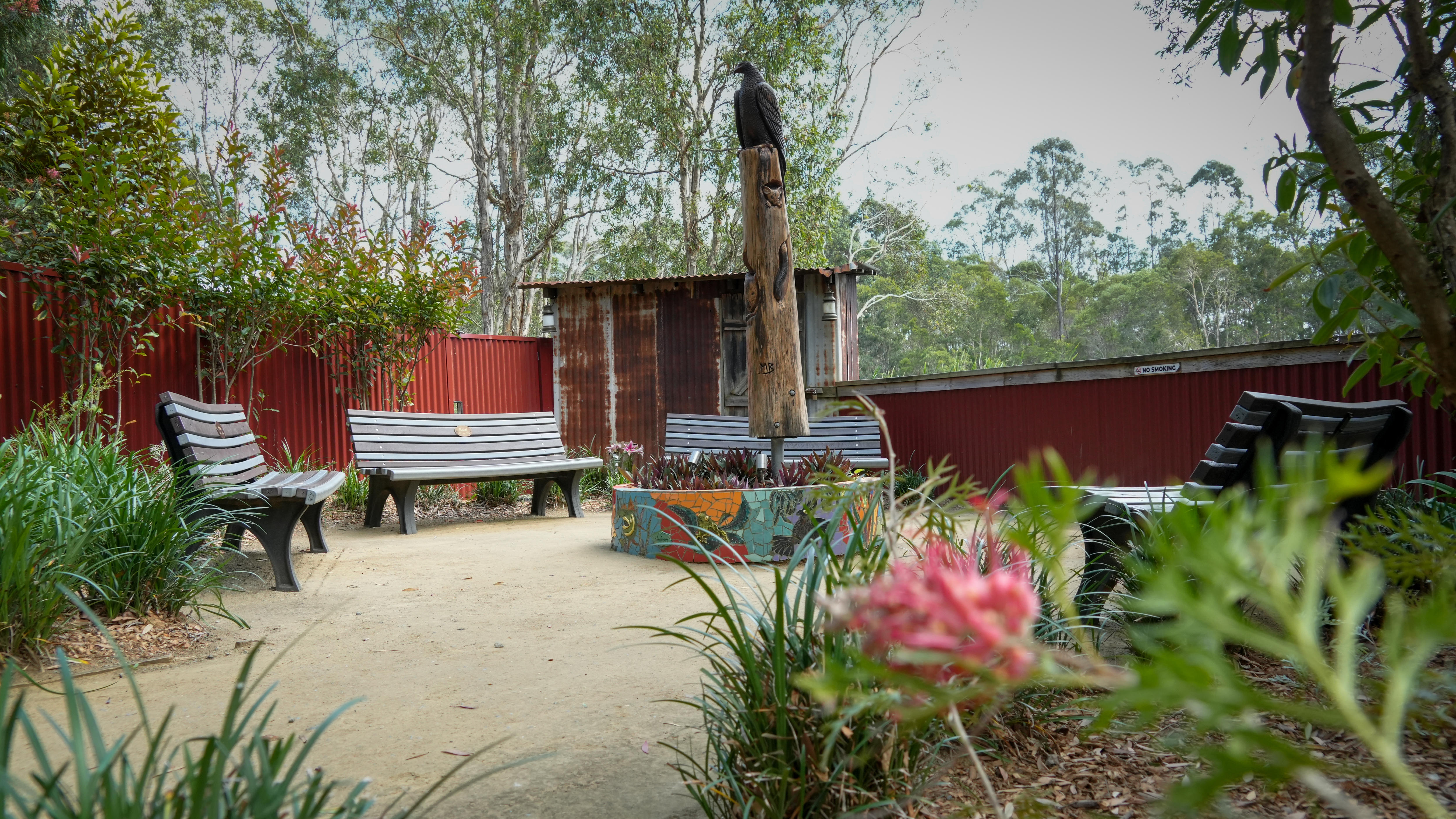 A garden with flowers and a pole with an eagle on top in the middle.