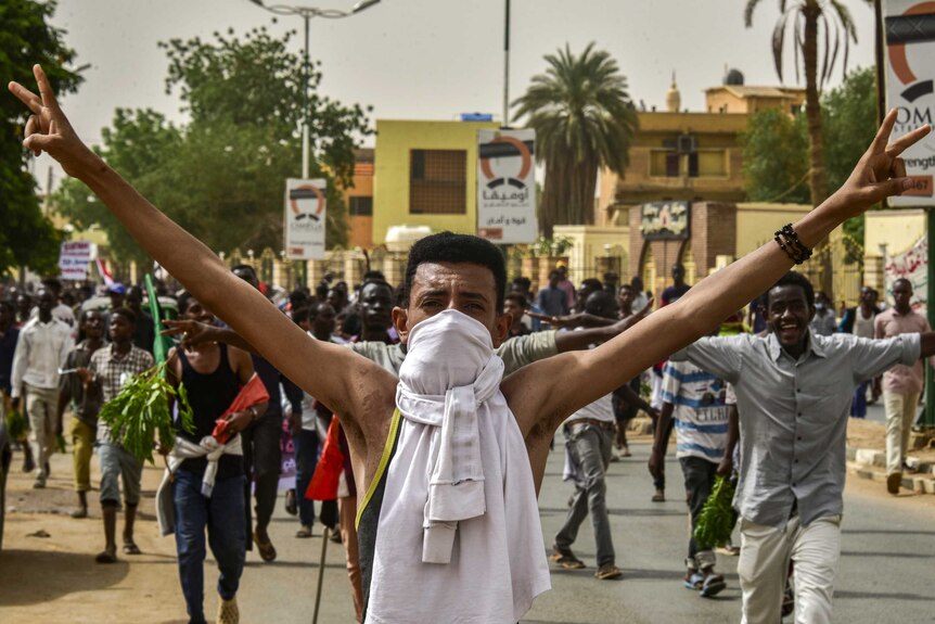 A Sudanese protester flashes the victory sign while marching in a mass demonstration in Khartoum.