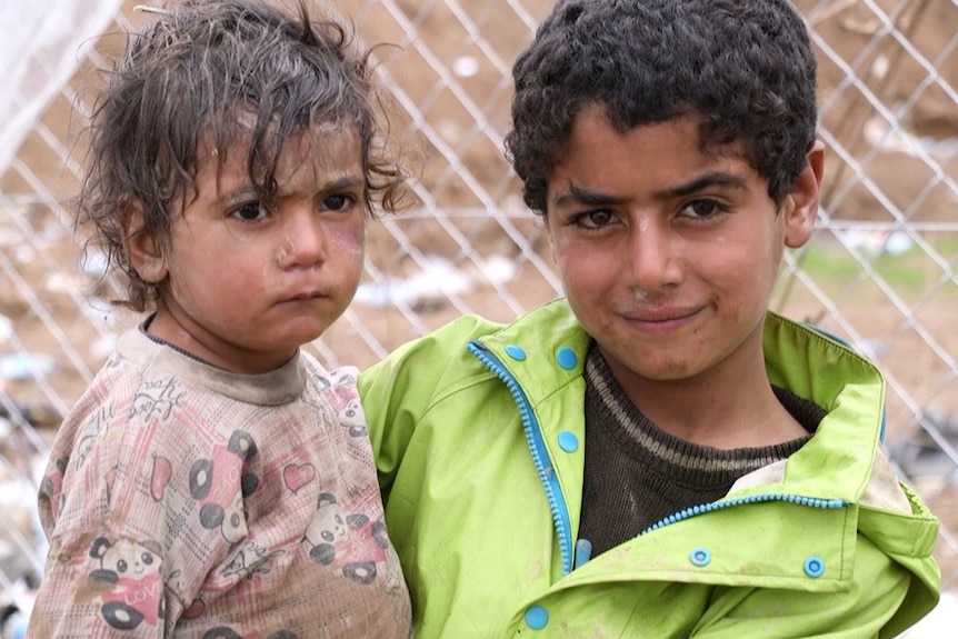 Two children, covered in dirt and close to tears, standing in the Hammam Al Alil camp south of Mosul.