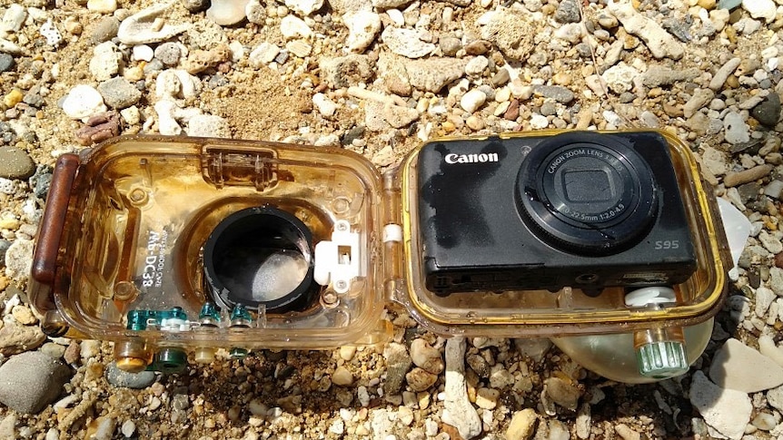 Digital camera in waterproof housing on beach