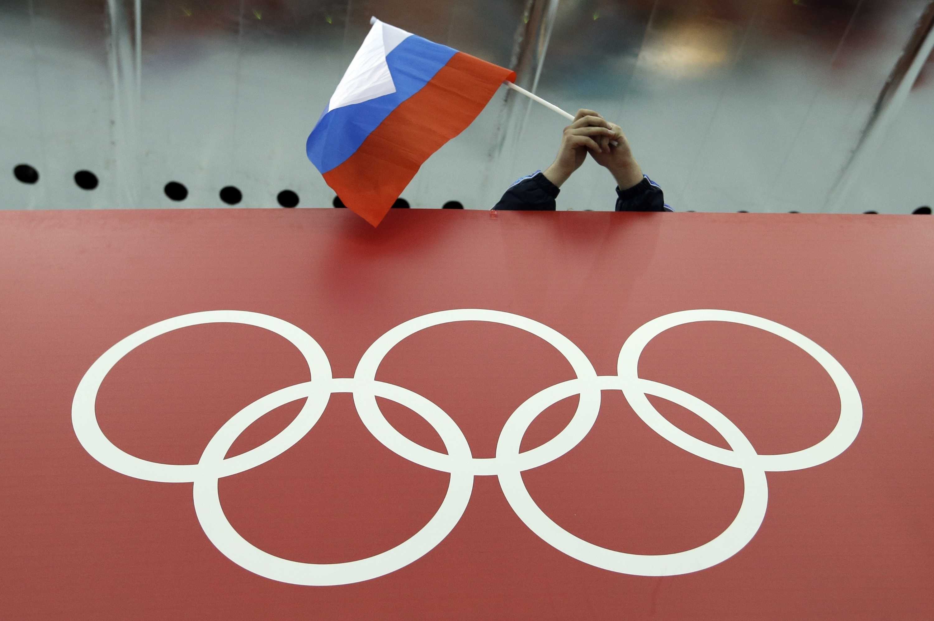 在索契奥运会期间，一名球迷在奥林匹克五环上高举俄罗斯国旗。
